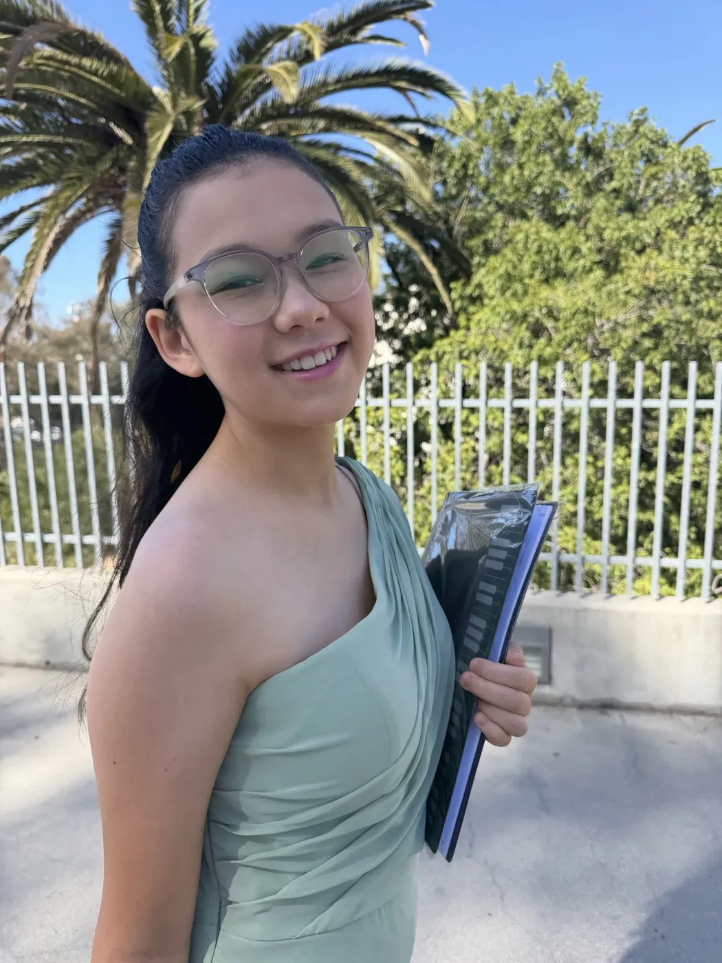 Chloe outside after her piano recital, holding her sheet music
